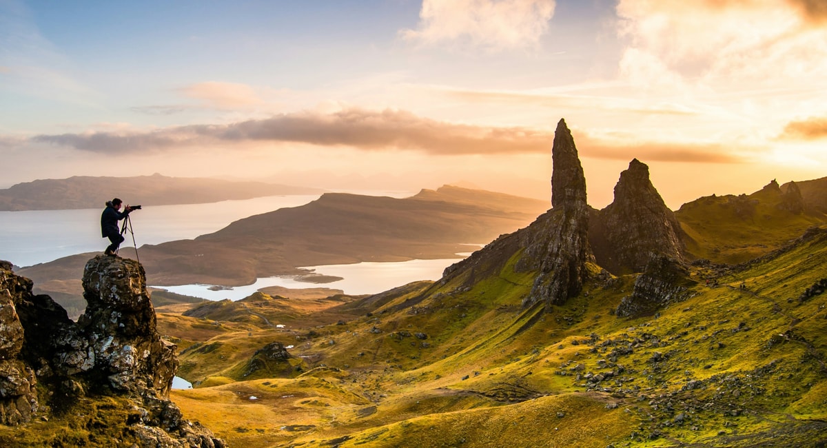 A hiker photographing the Old Man of Storr on the Isle of Skye at sunrise