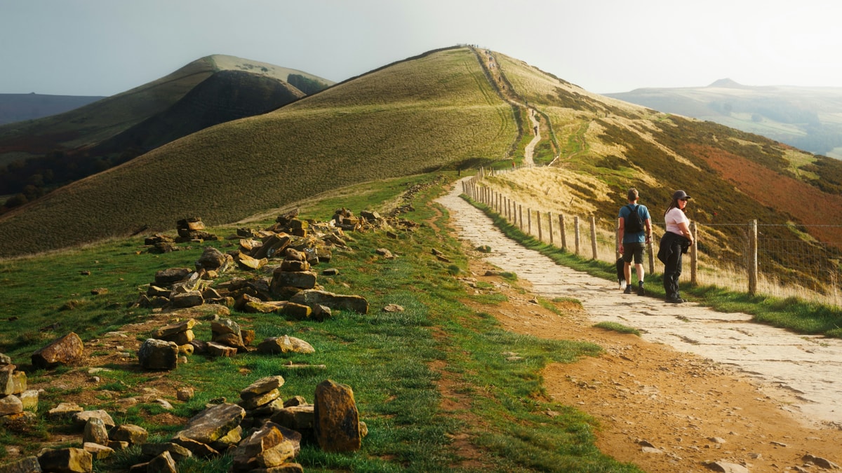 Walkers on the flagstone path along the Great Ridge from Mam Tor in the Peak District